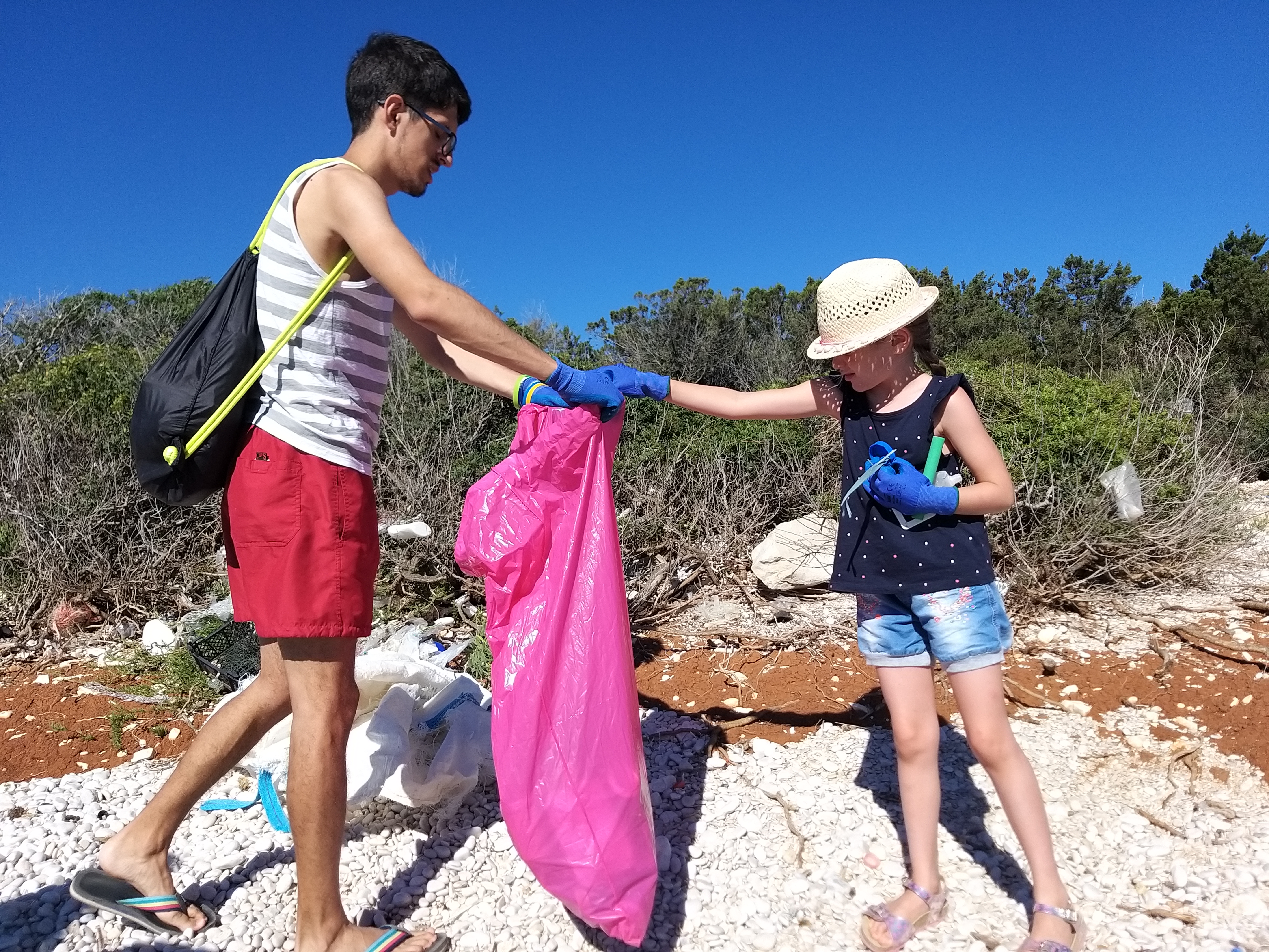 Volonter i djevojčica u akciji čišćenja morskog otpada na plaži
